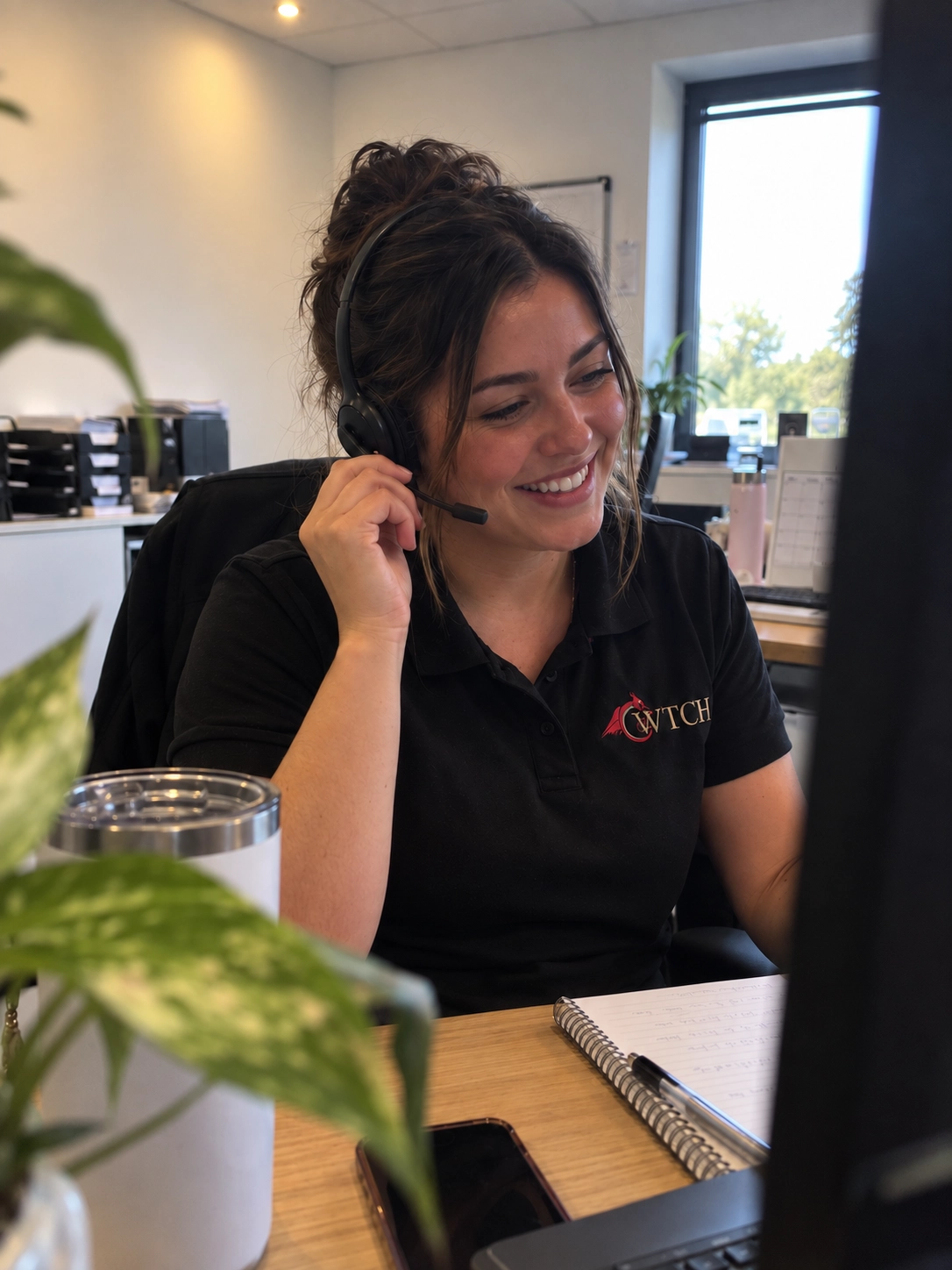 A member of the Cwtch Care team smiling while wearing a headset in the office